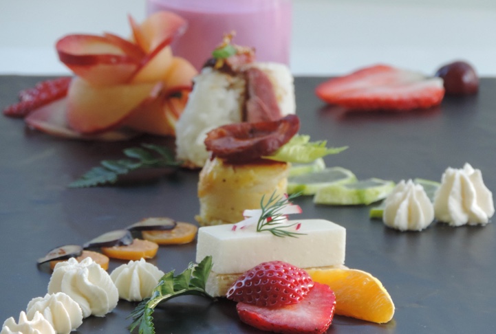 Présentation raffinée de bouchées sucrées et salées avec des fruits frais, crème et fromage, pour un cocktail dînatoire élégant préparé par un traiteur.